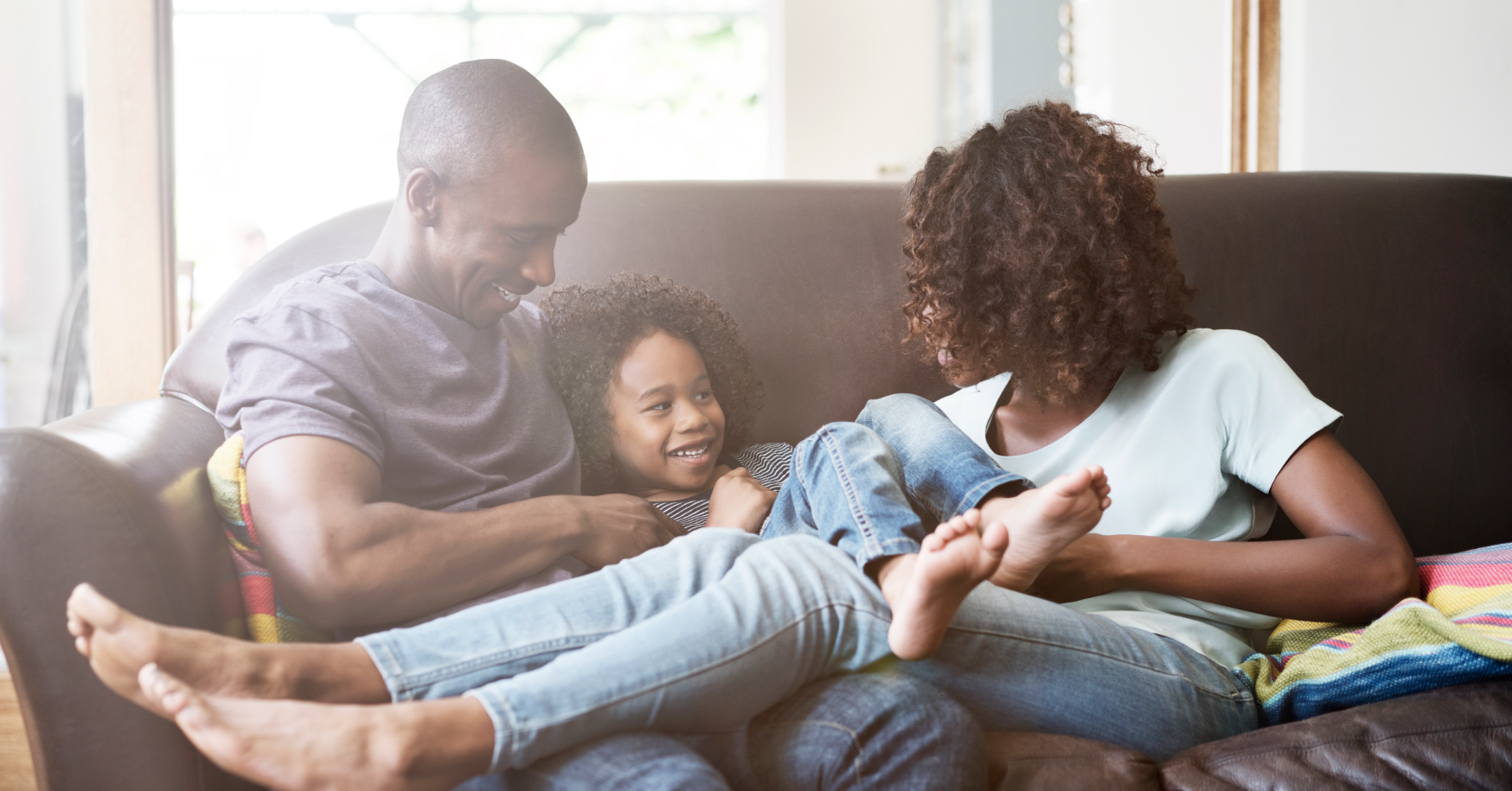 Mother and Father on couch playing with daughter