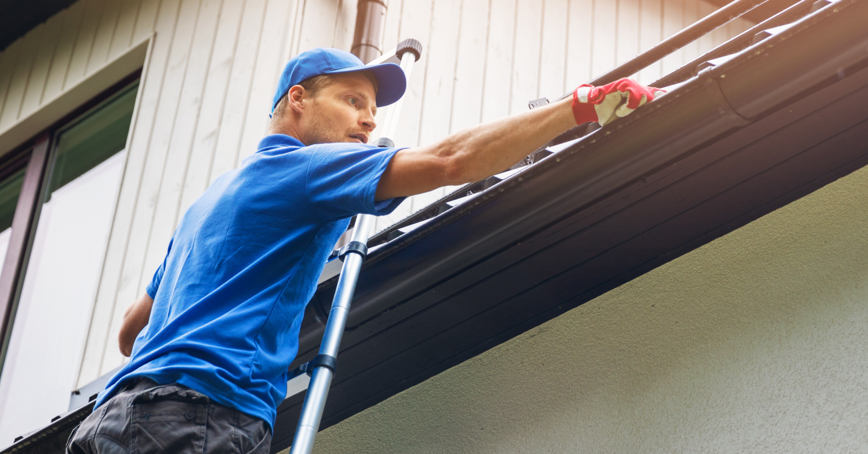 man on ladder cleaning gutters