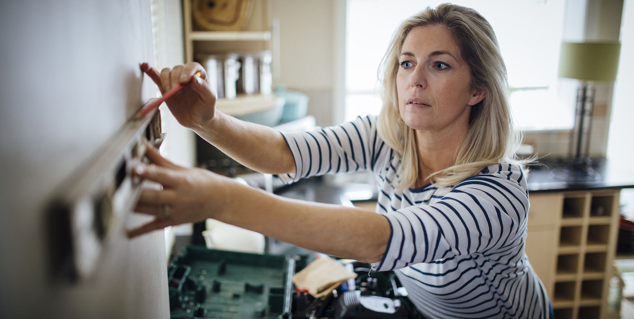 Woman using level to mark location of shelf on wall