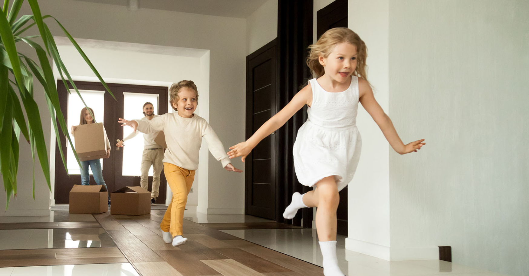 Brother and sister running into new home having the door opened by a realtor