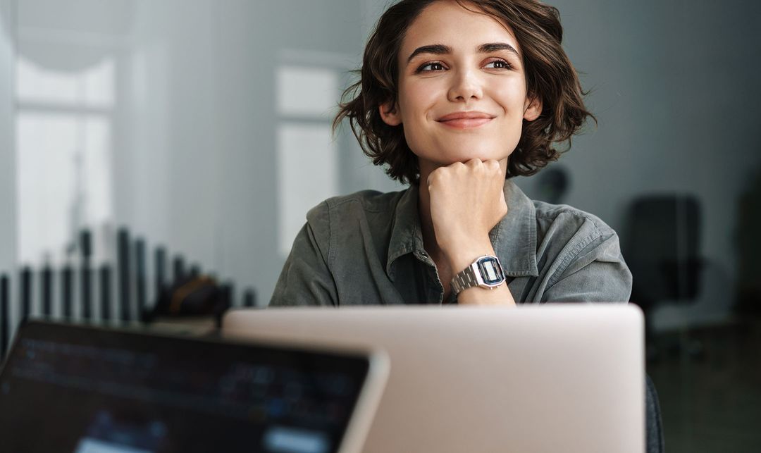 Woman smiling and thinking at a laptop