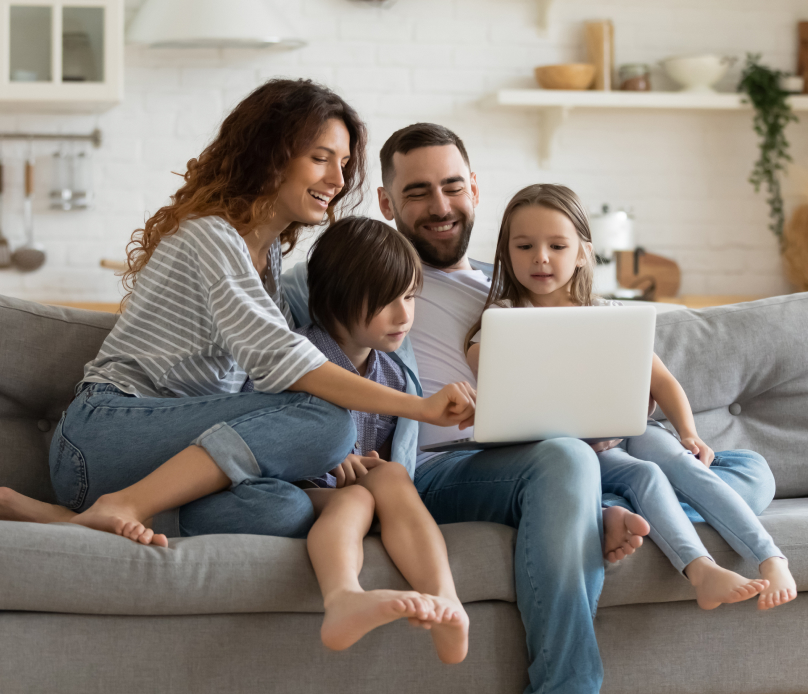 Happy Family Looking At A Computer On A Couch